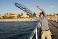 Young happy and proud attractive fisherman throwing fish and crabs basket net at sea dock sunset in man fishing as weekend hobby Royalty Free Stock Photo