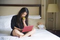 Young happy and relaxed Asian Chinese woman at hotel room bed working with laptop computer eating apple cheerful in business trave Royalty Free Stock Photo