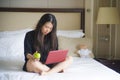 Young happy and relaxed Asian Korean woman at hotel room bed working with laptop computer eating apple cheerful in business travel Royalty Free Stock Photo