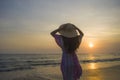 Young happy and relaxed woman in Summer hat looking at the sun over the sea during an amazing beautiful sunset at tropical paradis Royalty Free Stock Photo