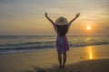 Young happy and relaxed woman in Summer hat looking at the sun over the sea during an amazing beautiful sunset at tropical paradis Royalty Free Stock Photo