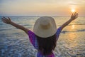 Young happy and relaxed woman in Summer hat looking at the sun over the sea during an amazing beautiful sunset at tropical paradis Royalty Free Stock Photo