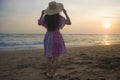 Young happy and relaxed woman in Summer hat looking at the sun over the sea during an amazing beautiful sunset at tropical paradis Royalty Free Stock Photo