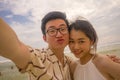 Young happy and romantic Asian Korean couple in love enjoying holiday taking selfie photo together on beautiful beach having fun Royalty Free Stock Photo