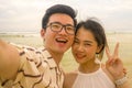 Young happy and romantic Asian Korean couple in love enjoying holiday taking selfie photo together on beautiful beach having fun Royalty Free Stock Photo