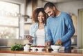 Young, happy and romantic couple cooking healthy food together following recipes online on a tablet. Smiling husband and Royalty Free Stock Photo