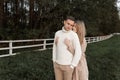 Young happy romantic pregnant couple is walking holding hands outdoors at autumn warm day. Pregnant woman in knit dress Royalty Free Stock Photo