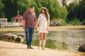 Young happy romantic pregnant couple are walking on nature near lake in summer park. Pregnant woman expecting a baby. Future mom Royalty Free Stock Photo
