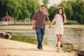 Young happy romantic pregnant couple are walking on nature near lake in summer park. Pregnant woman expecting a baby. Future mom Royalty Free Stock Photo