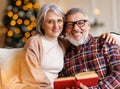 Young happy senior family couple in love enjoying Christmas holidays together at home, reading book Royalty Free Stock Photo