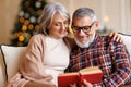 Young happy senior family couple in love enjoying Christmas holidays together at home, reading book Royalty Free Stock Photo