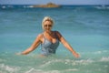 Young happy and sexy blond woman in swimsuit bikini playing with waves in the sea at stunning beautiful tropical beach enjoying Royalty Free Stock Photo