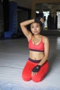 sweaty Asian woman in sport clothes stretching tired and exhausted on gym dojo floor after hard training