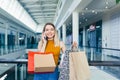 Young happy after shopping woman talking on cell in mall. Satisfied joyful female shopaholic with gift colored paper bags in hands Royalty Free Stock Photo