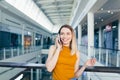 Young happy after shopping woman talking on cell in mall. Satisfied joyful female shopaholic with gift colored paper bags in hands Royalty Free Stock Photo