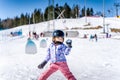 Young happy skier girl throwing snowballs in snowball fight