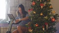 Young happy slim woman riding a stationary bike with a smart clock after the Christmas holidays next to the christmas Royalty Free Stock Photo