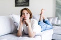 Young happy smile woman phone call on sofa in living room, at home. Excited girl lying talking cellphone Royalty Free Stock Photo