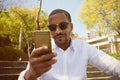 Young happy smiling african american male in sun glasses with mobile phone in city garden park. Royalty Free Stock Photo