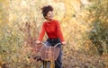 Young happy smiling african american woman riding bicycle in autumn forest, active positive mixed-race female in casual clothes Royalty Free Stock Photo