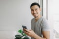 Young happy smiling asian man using smartphone feels relax and comfortable. Royalty Free Stock Photo
