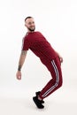 Young happy smiling bearded man with short dark hair in red striped sport wear, black sneakers, posing standing on toes. Royalty Free Stock Photo