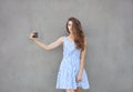 Young happy smiling beautiful woman in light dress with long brunette curly hair posing against wall on a warm Royalty Free Stock Photo