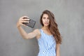 Young happy smiling beautiful woman in light dress with long brunette curly hair posing against wall on a warm Royalty Free Stock Photo