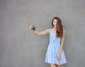 Young happy smiling beautiful woman in light dress with long brunette curly hair posing against wall on a warm Royalty Free Stock Photo