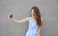 Young happy smiling beautiful woman in light dress with long brunette curly hair posing against wall on a warm Royalty Free Stock Photo