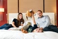 Young happy smiling Caucasian family of father, mother and daughter lying together on bed in hotel bedroom while having vacation Royalty Free Stock Photo