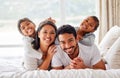 Young happy smiling couple looking cheerful and relaxed while sharing the bed with their daughters. Two girls being Royalty Free Stock Photo