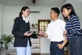 Young happy smiling couple read agreement with realtor and looking through the contract of real estate sale going to Royalty Free Stock Photo