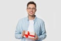 Young happy smiling guy in eyeglasses holding present. Royalty Free Stock Photo