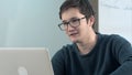 Young happy smiling guy using laptop for video conversation in school