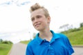 Young happy smiling male boy teenager blond child outside in summer sunshine wearing a blue sweatshirt Royalty Free Stock Photo