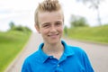 Young happy smiling male boy teenager blond child outside in summer sunshine wearing a blue sweatshirt Royalty Free Stock Photo