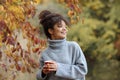 Young happy smiling mixed-race woman with coffee cup in autumn nature Royalty Free Stock Photo