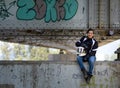 Young happy smiling pretty female motorcyclist posing on a bridge