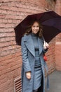 Young happy smiling pretty girl in gray coat and turtleneck poses with umbrella Royalty Free Stock Photo