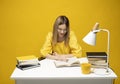 Young happy smiling student woman in yellow casual clothes reading the book at the table in library of university or Royalty Free Stock Photo