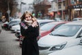 Young happy smiling woman in black coat and scarf walking around city. Waiting for her boyfriend. Waiting for meeting Royalty Free Stock Photo