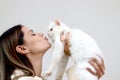 Young happy smiling woman holding cute white Persian cat and lift up her cat, try to kiss her pet, happy beautiful lady playing Royalty Free Stock Photo