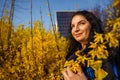 Young happy smiling woman plus size in spring in city park among blooming yellow forsythia bushes Royalty Free Stock Photo
