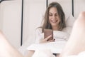 Young happy smiling woman using her phone while lying in bed in the morning. Awakening. Girl reads good news, social Royalty Free Stock Photo