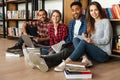 Young happy students sitting in library on floor. Royalty Free Stock Photo