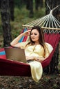 Young happy successful woman freelancer with laptop relaxing in the hammock on summer Pine forest on sunny day. Female Royalty Free Stock Photo