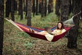 Young happy successful woman freelancer with laptop relaxing in the hammock on summer Pine forest on sunny day. Female Royalty Free Stock Photo