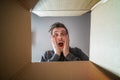 Young happy surprised man is opening gift and looking inside cardboard box. Royalty Free Stock Photo