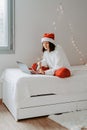 Young happy teen girl in red santa hat shopping online buying Christmas gifts Royalty Free Stock Photo